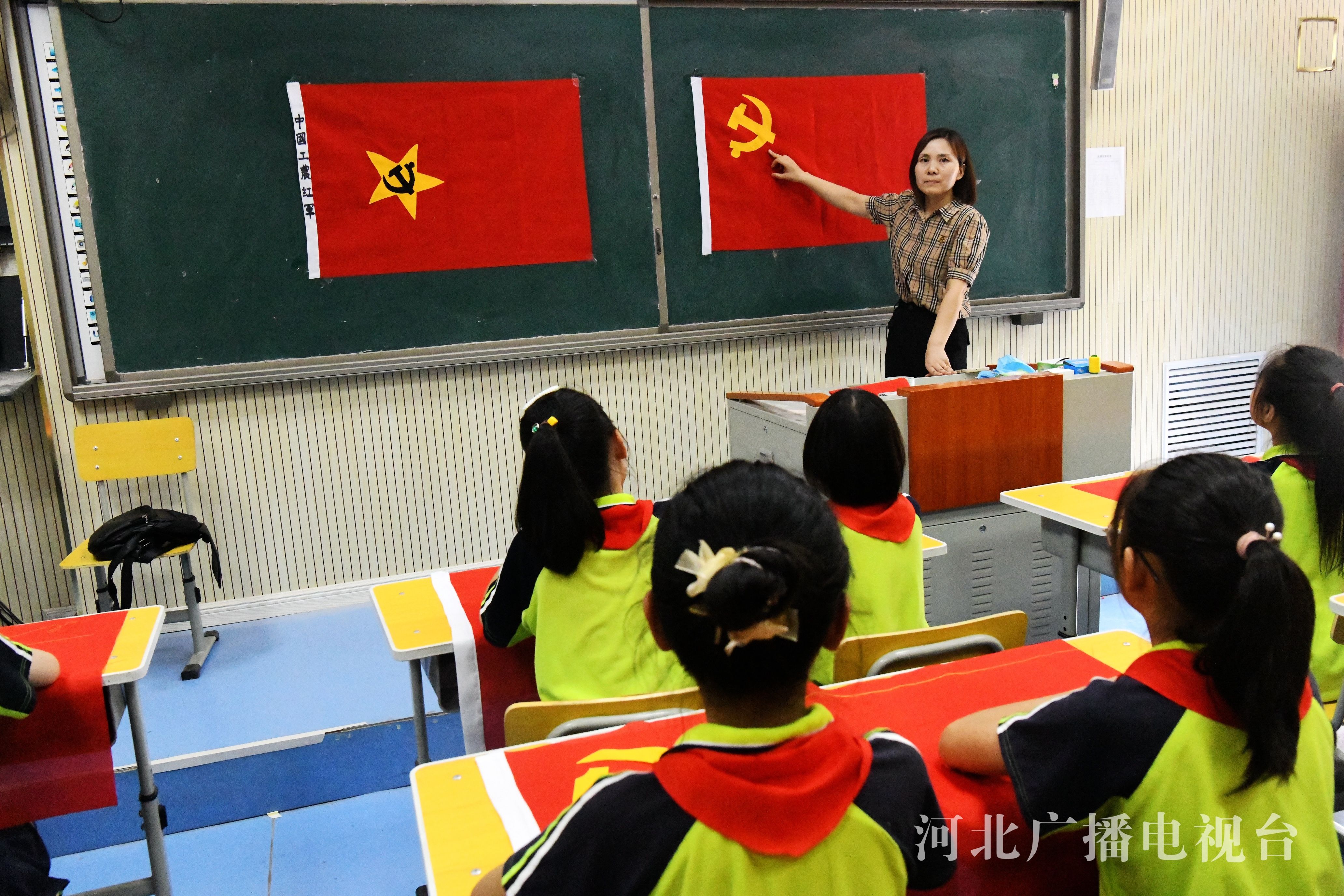 学生在老师的指导下一针一线绣党旗